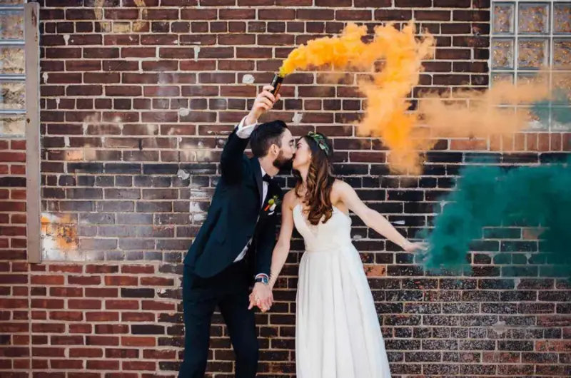 noivos segurando fuma&ccedil;a colorida