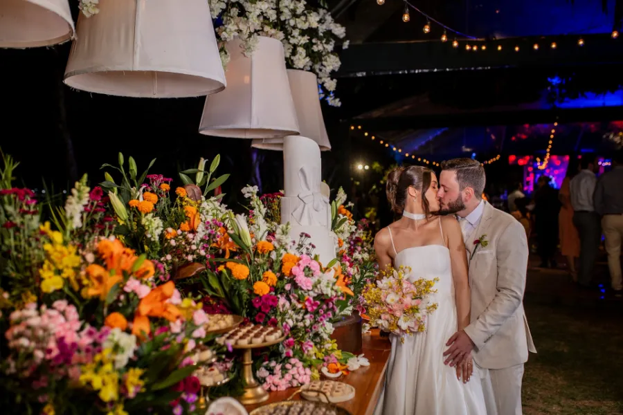 noivos se beijando na frente da mesa do bolo