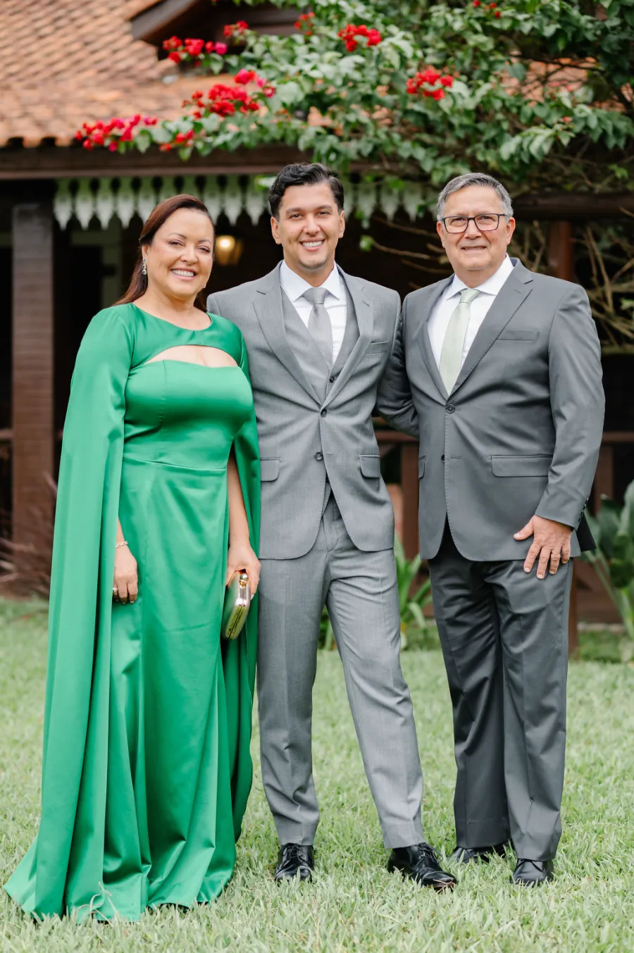 noivo de terno cinz ao lado da mãe com vestido ver de pai com terno cinza