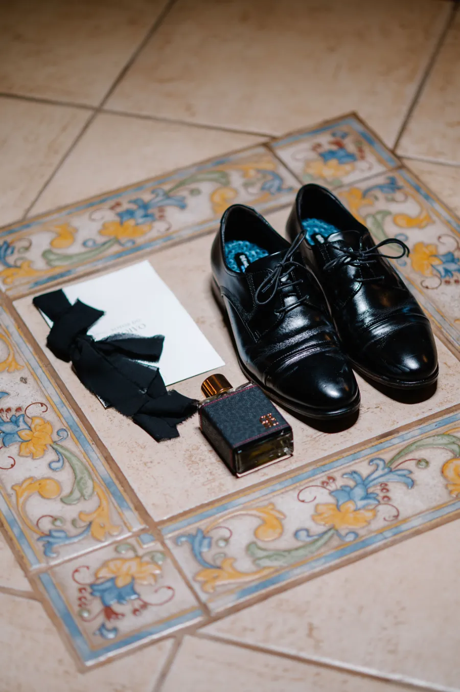 sapato preto de couro ao lado de perfuem e caderno de votos