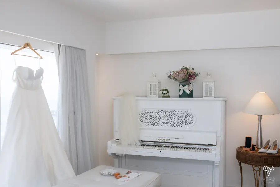 vestido de noiva pendurado na frente da janela ao lado de piano