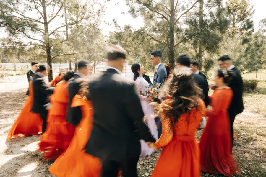 Momento de celebração com os noivos rodeados por padrinhos e madrinhas em vestidos cor terracota, em um casamento terracota animado.