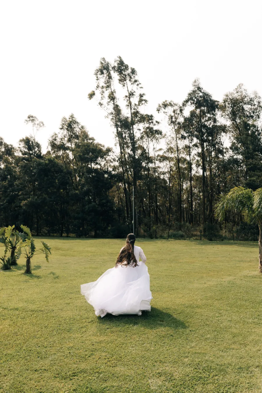 A noiva corre em um campo gramado com seu vestido esvoaçante, capturando a liberdade