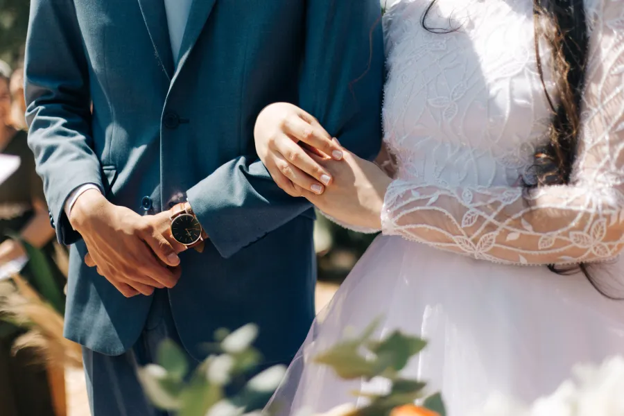 Close-up das mãos dos noivos durante a cerimônia, detalhe de um casamento terracota.