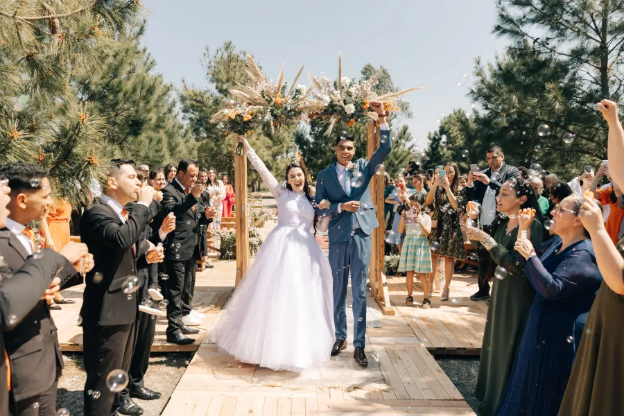 Os noivos celebram ao final da cerimônia enquanto convidados sopram bolhas