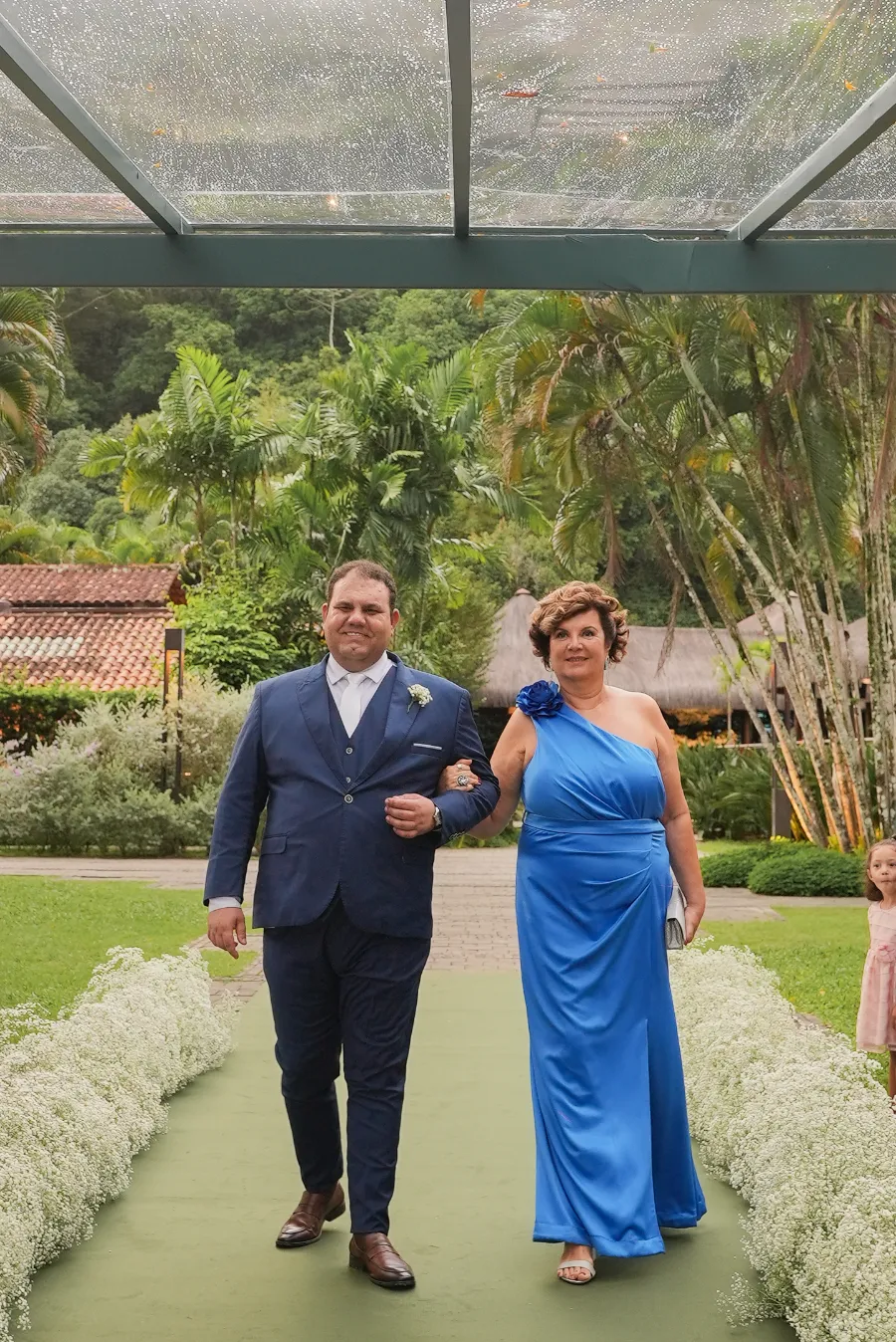 entrada do noivo com terno azul ao lado da mãe com vestido azul