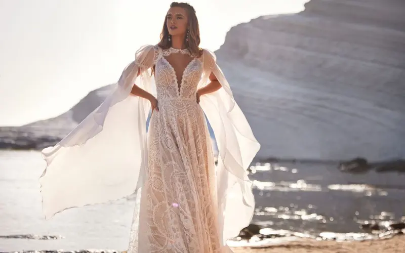 modelo com vestido de noiva flu&iacute;do na praia
