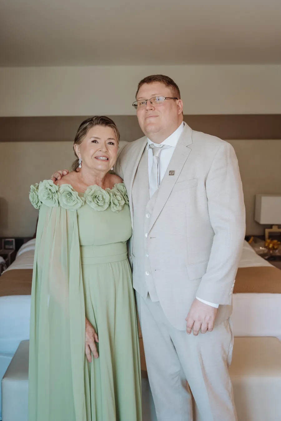 noivo com terno claro ao lado da mãe com vestido verde com capa