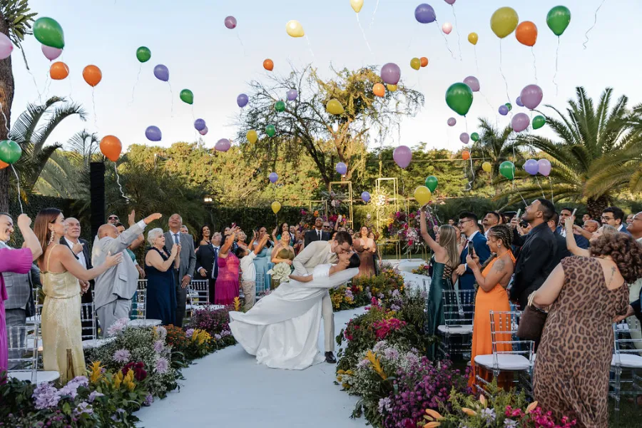 noivos se beijando na saída com balões