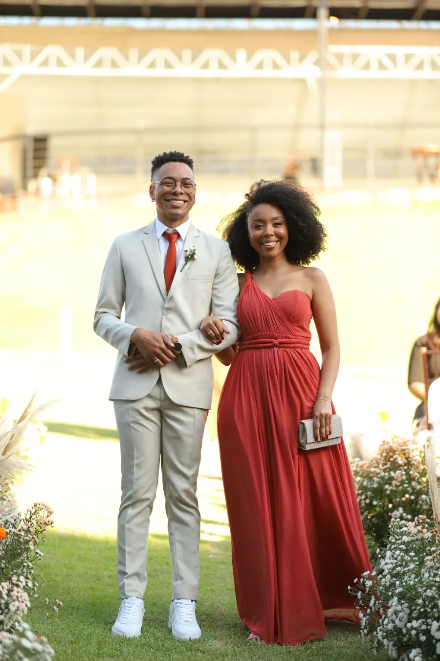 madrinha de vestido terracota ao lado do padrinho com terno cinza claro