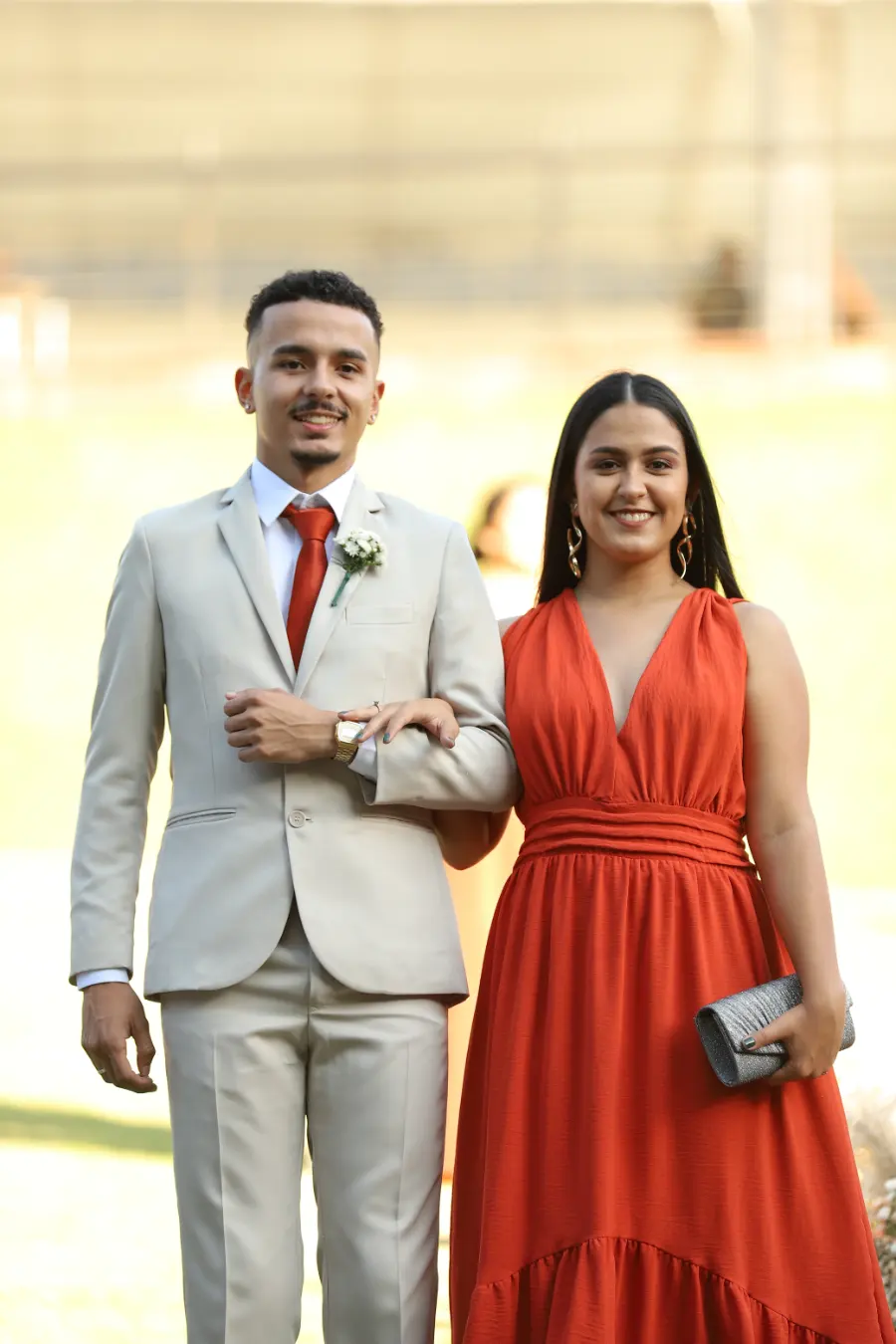 madrinha de vestido terracota ao lado do padrinho com terno cinza claro