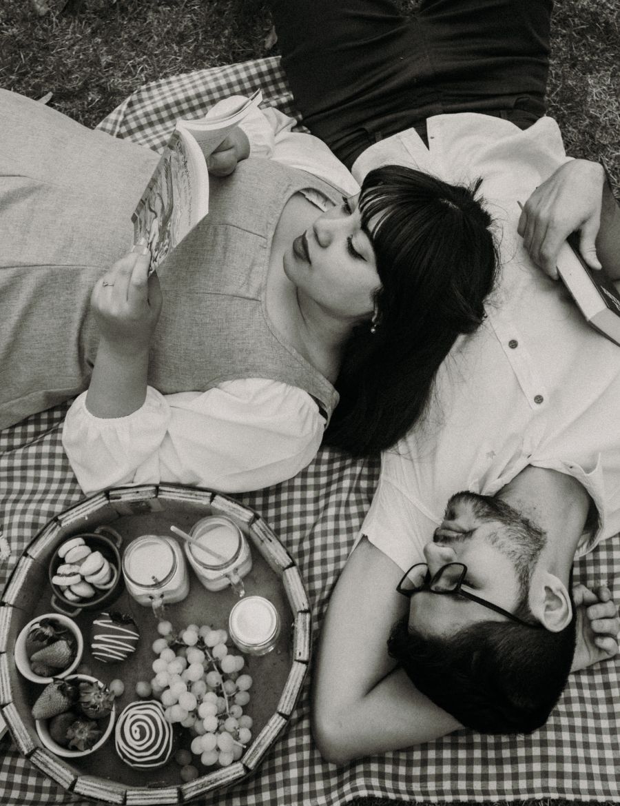 Casal lendo livros em piquenique inspirado em A Bela e a Fera