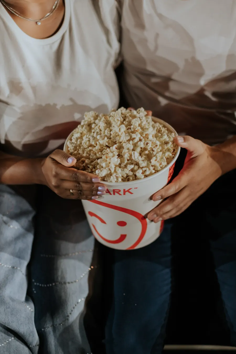 casal segurando balde de pipoca