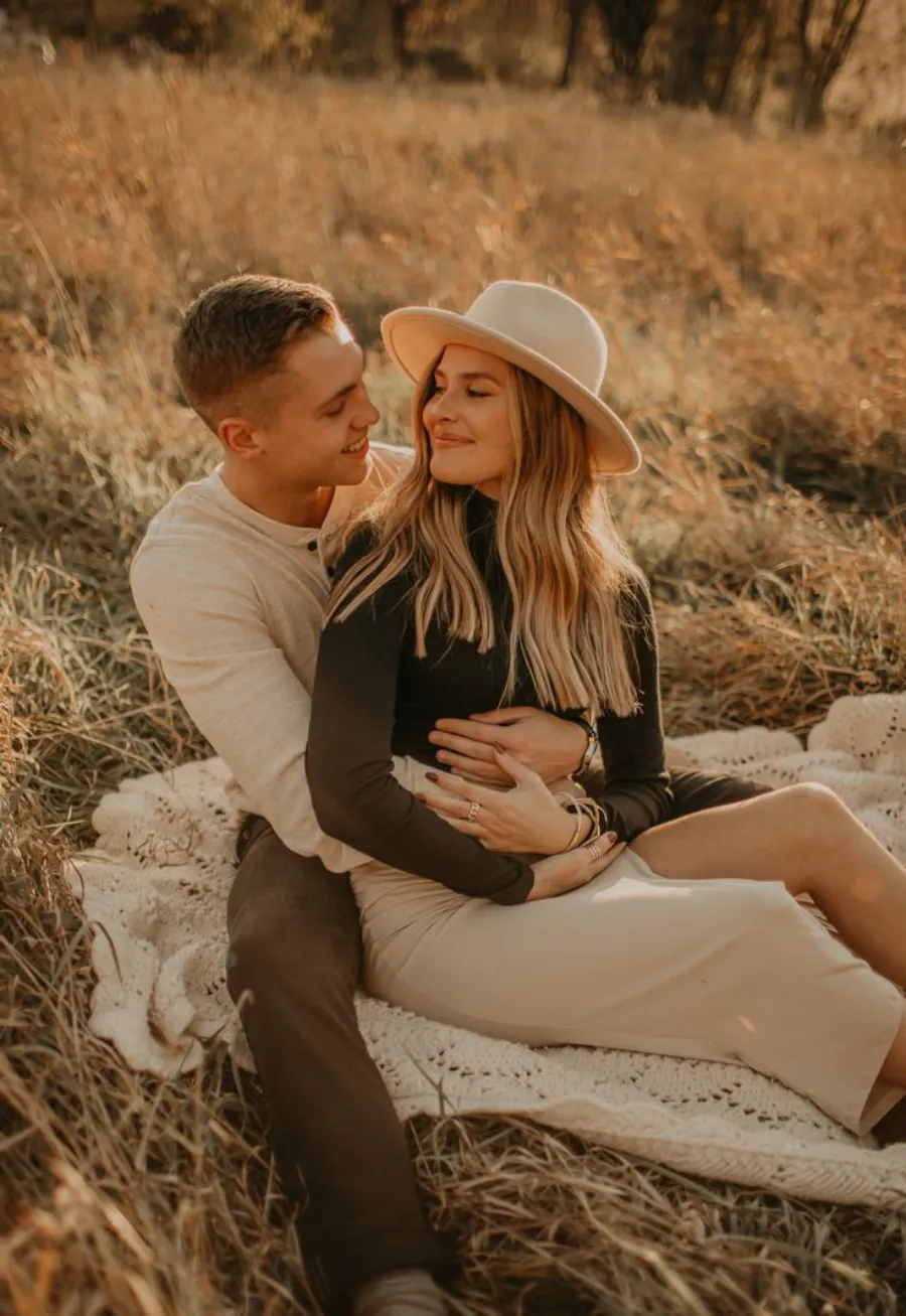 mulher usando vestido de pré wedding com chapéu abraçada com o noivo