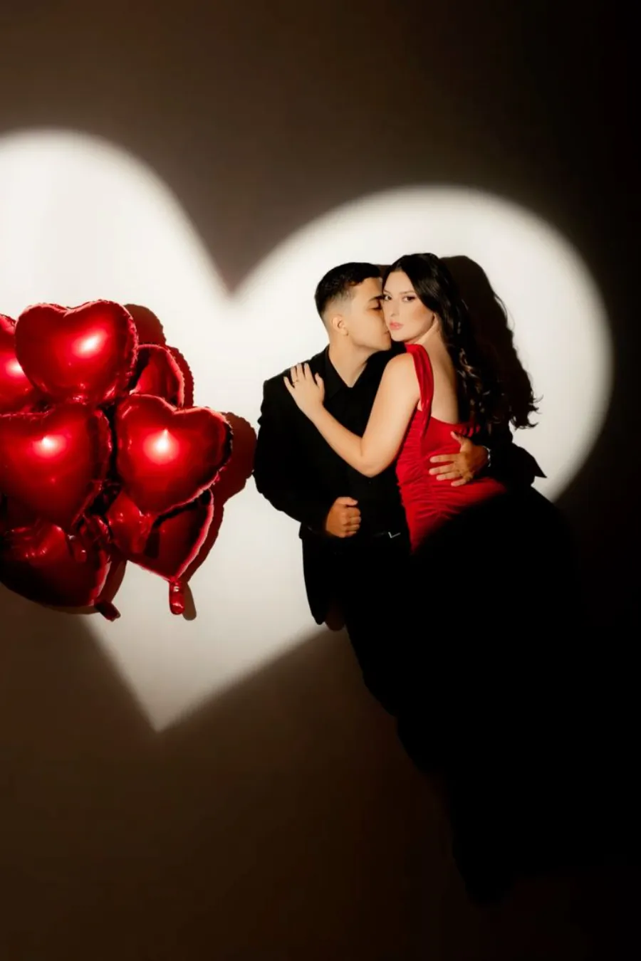 casal abraçado ao lado de balões de corações vermelhos para comemorar bodas de namoro