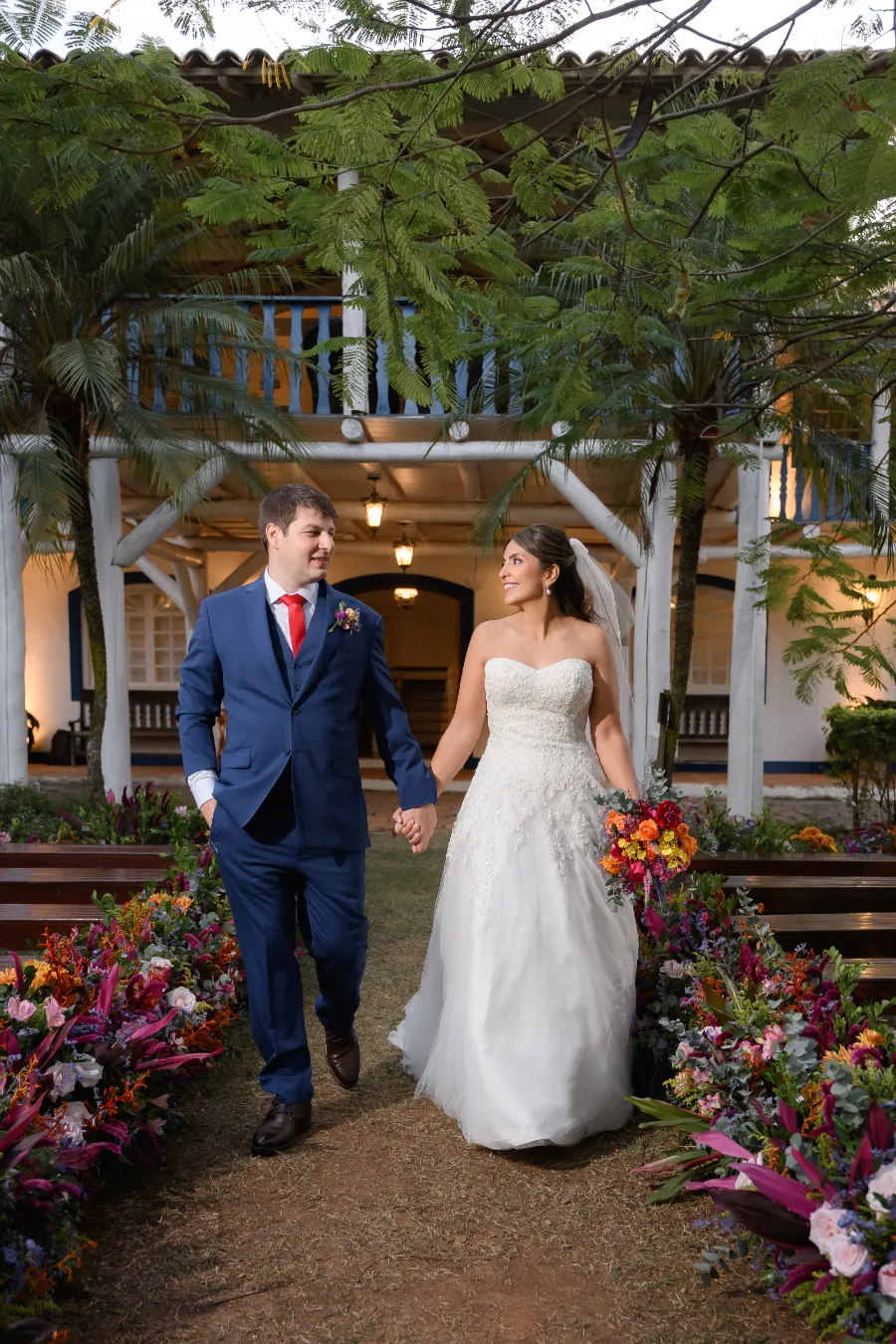 noivos andando de mãos dadas no casamento colorido