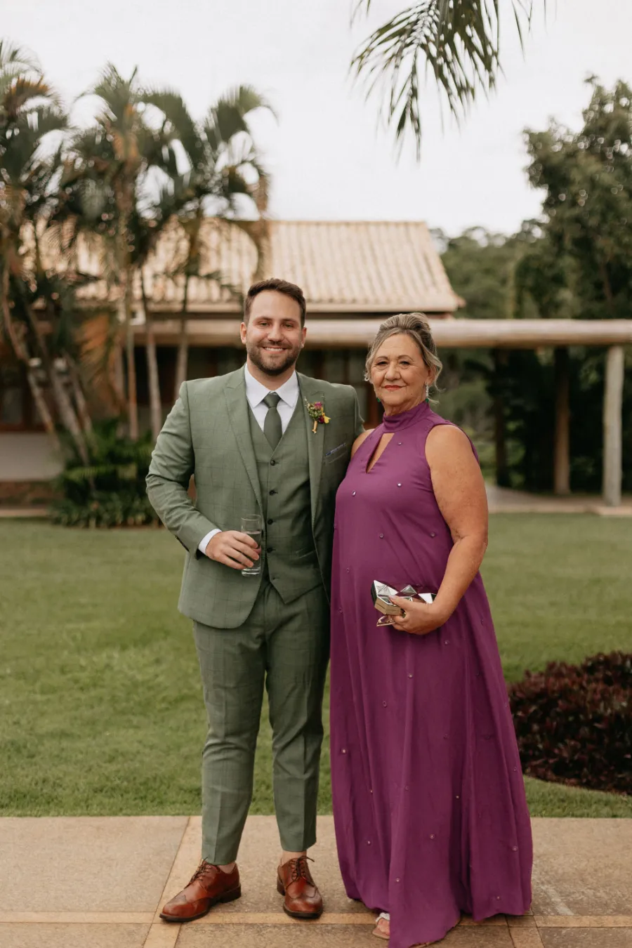 noivo de terno verde oliva ao lado da mãe de vestido roxo