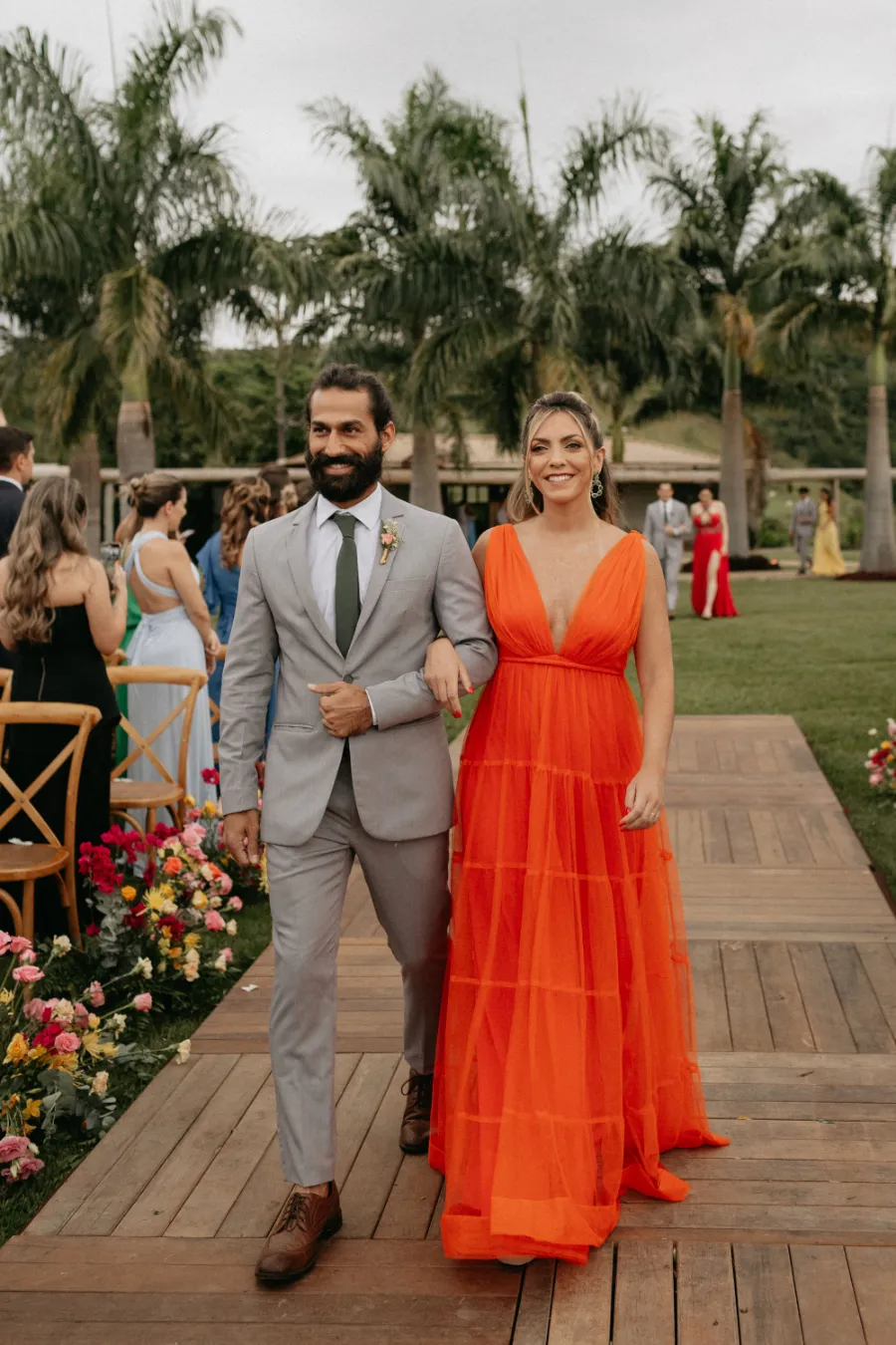 entrada da madrinha de vestido laranja e padrinho de terno cinza