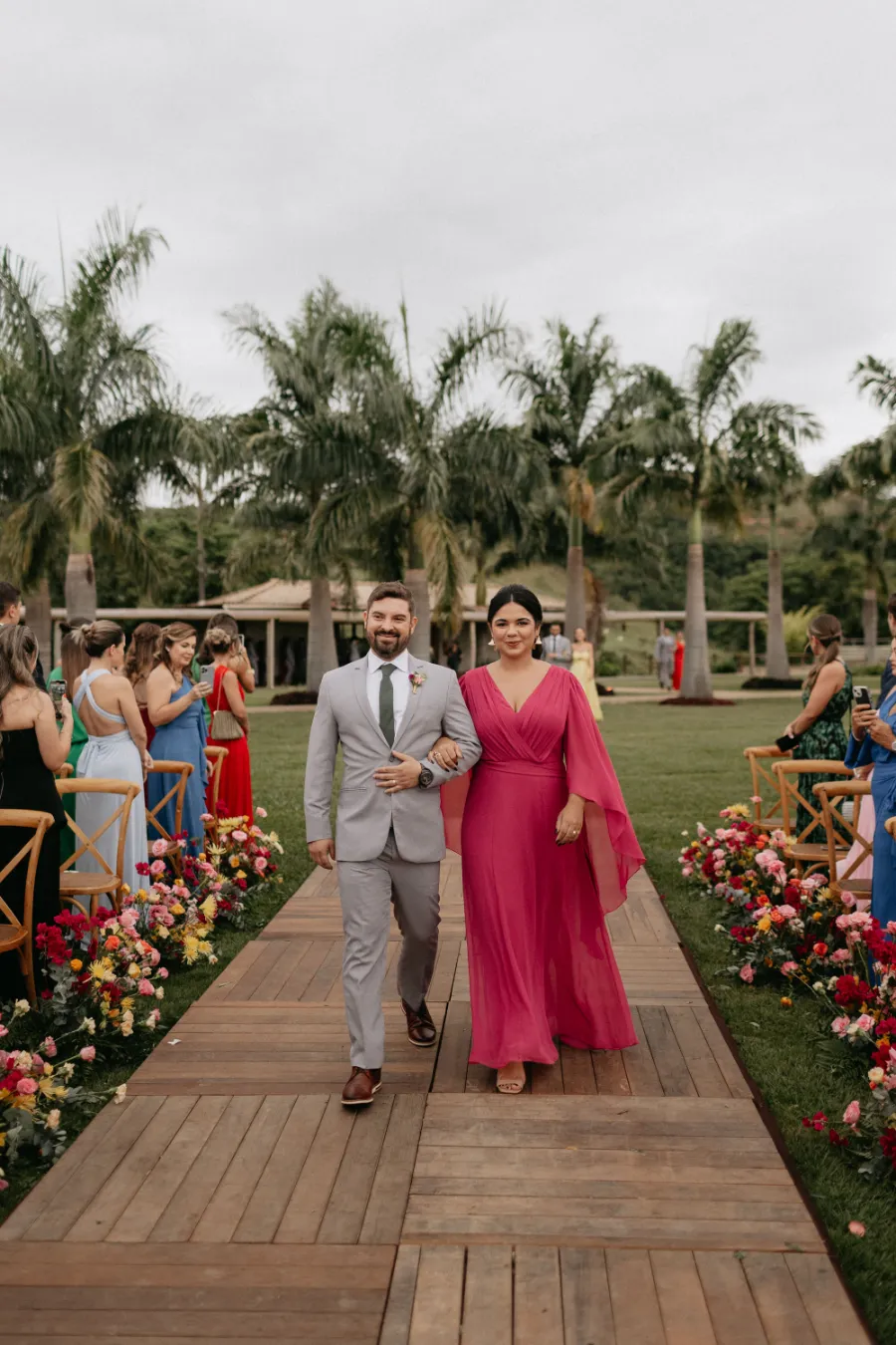 entrada da madrinha de vestido rosa e padrinho de terno cinza