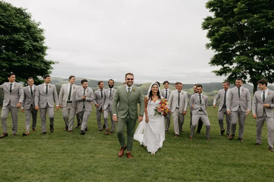 noivos andando e padrinhos de terno cinza