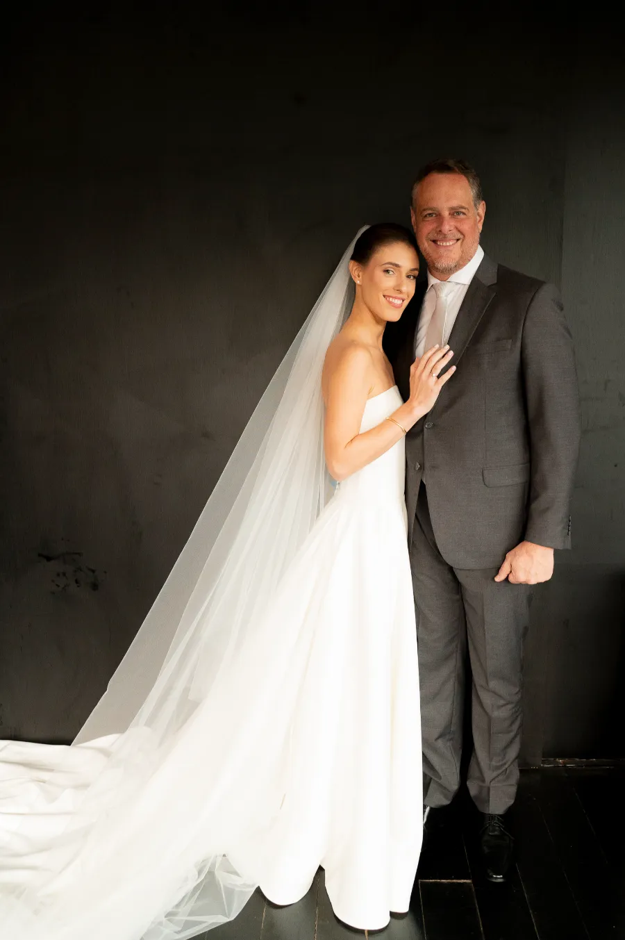 noiva com vestido minimalista com véu abraçada ao pai com terno cinza
