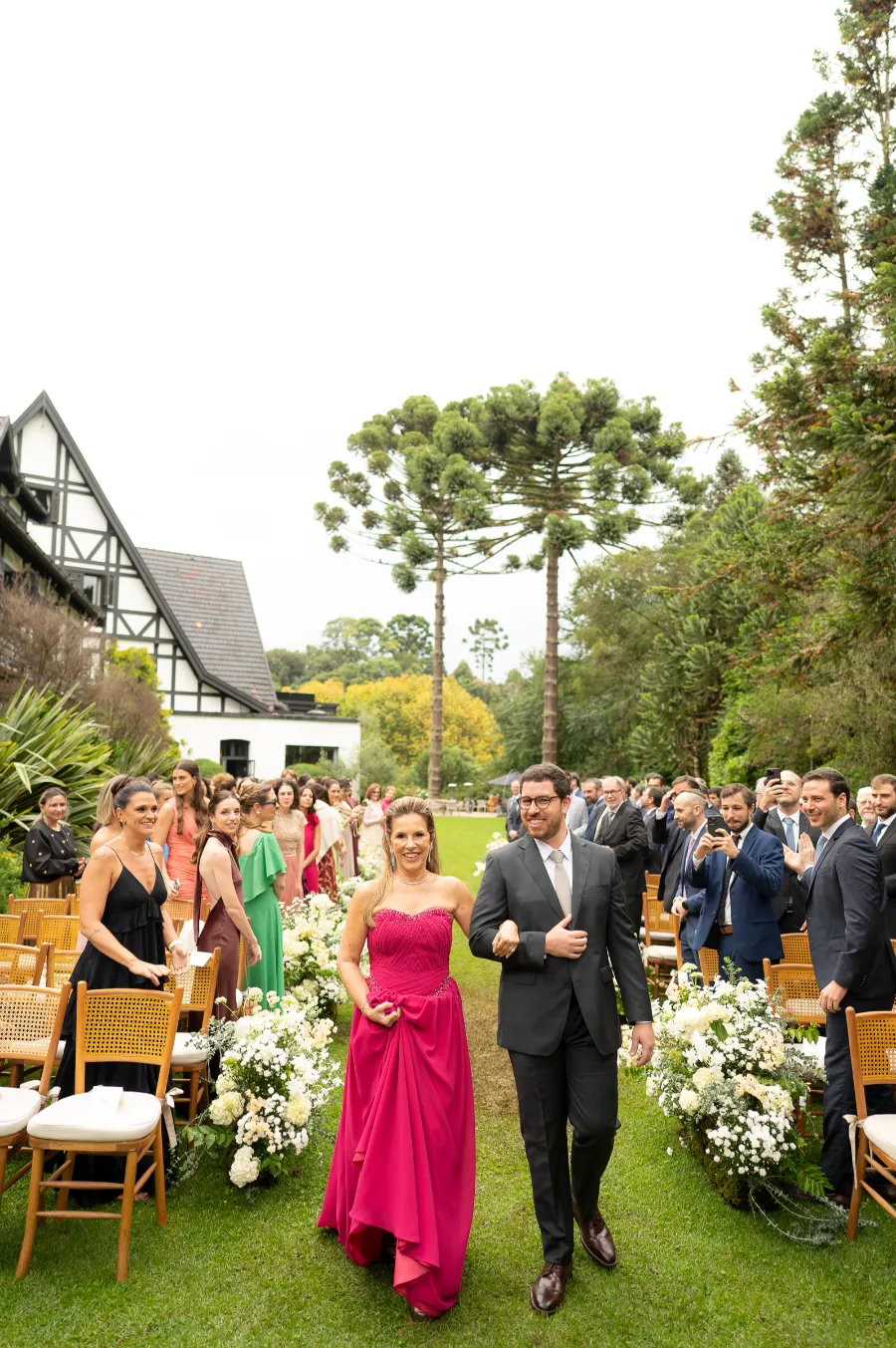 entrada do noivo com terno cinza ao lado da mãe com vestido rosa