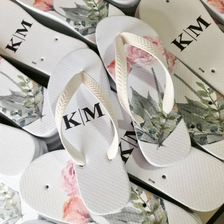 Chinelos personalizados brancos com iniciais K e M e estampa floral delicada.