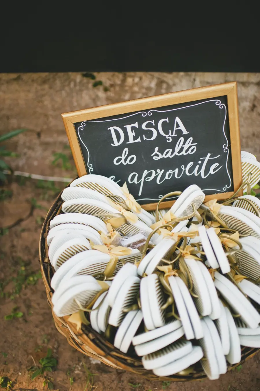 Chinelos personalizados em cesta com plaquinha escrita "Desça do salto e aproveite" em casamento.