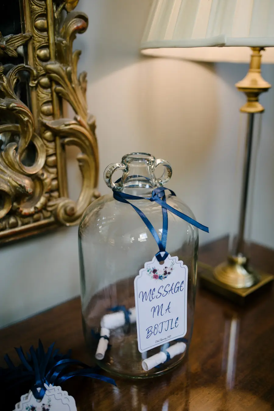 Um grande recipiente de vidro com pequenas mensagens enroladas e presas com fitas, criando o efeito de “mensagens na garrafa”.