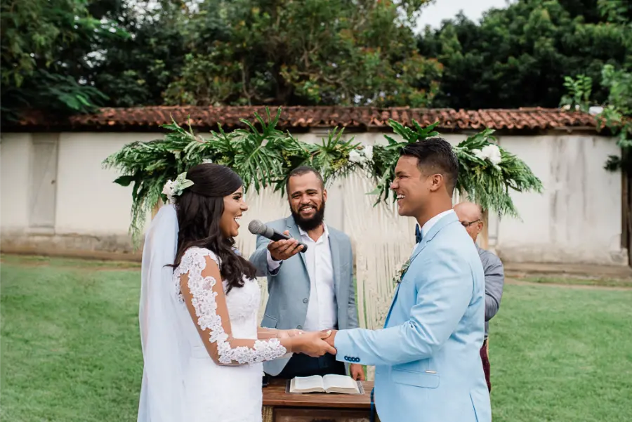 Noiva e noivo trocando votos com microfone em cerim&ocirc;nia ao ar livre