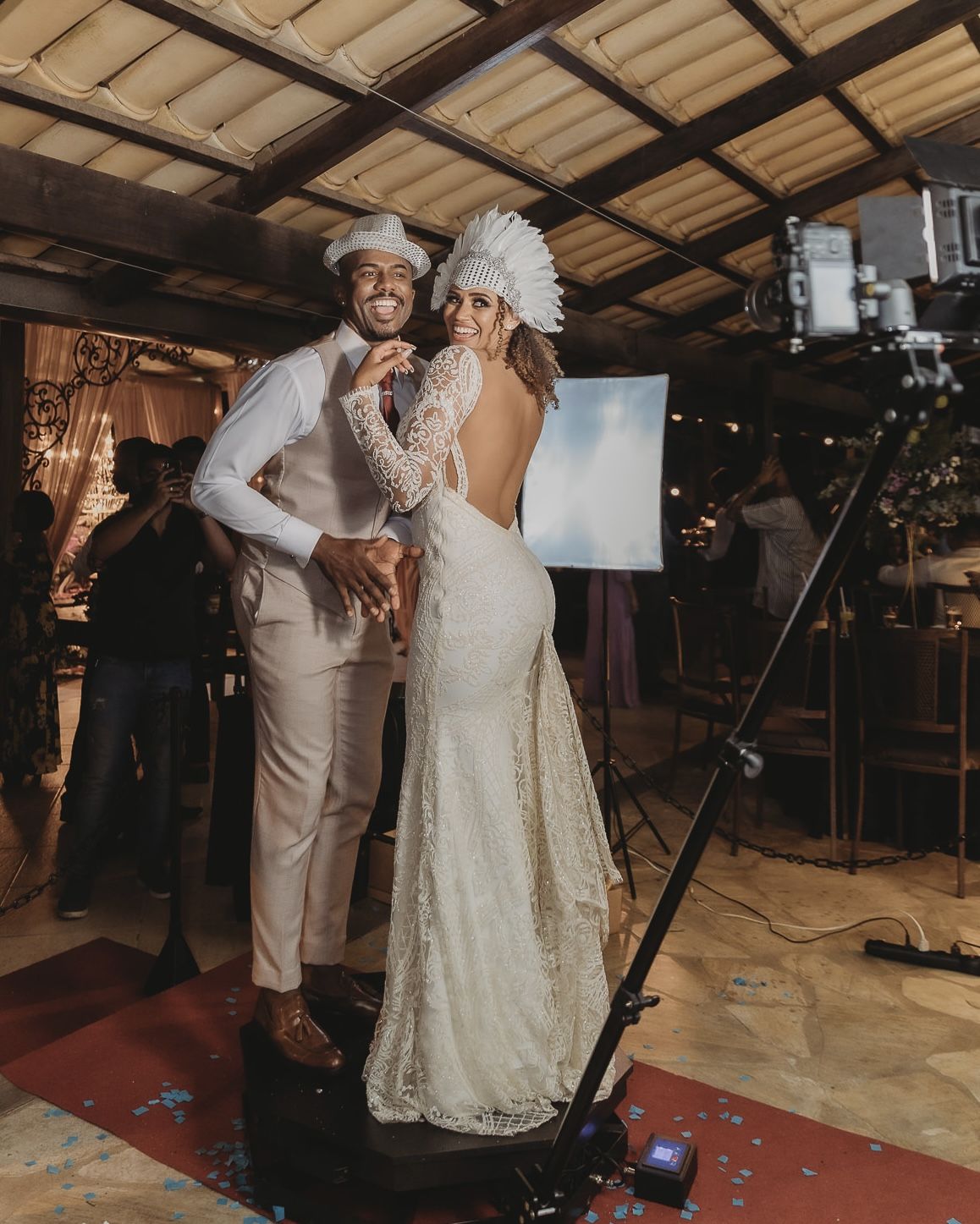 Noivos posando em plataforma 360 durante o casamento, usando chapéus divertidos enquanto a câmera registra o momento.