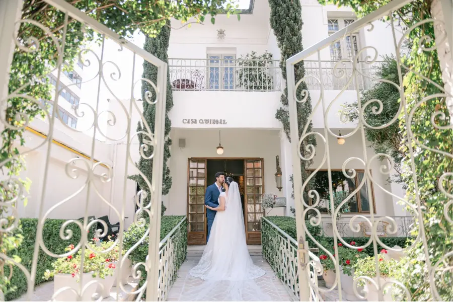 Casal de noivos em frente à Casa Quintal, espaço para casamentos intimistas com jardim e arquitetura clássica.