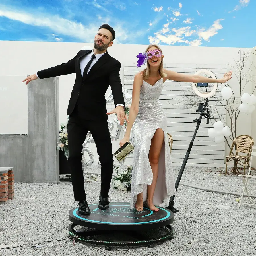 Noivos se divertindo em uma plataforma 360 durante o casamento ao ar livre, vestidos elegantemente e fazendo poses para o vídeo em 360 graus.