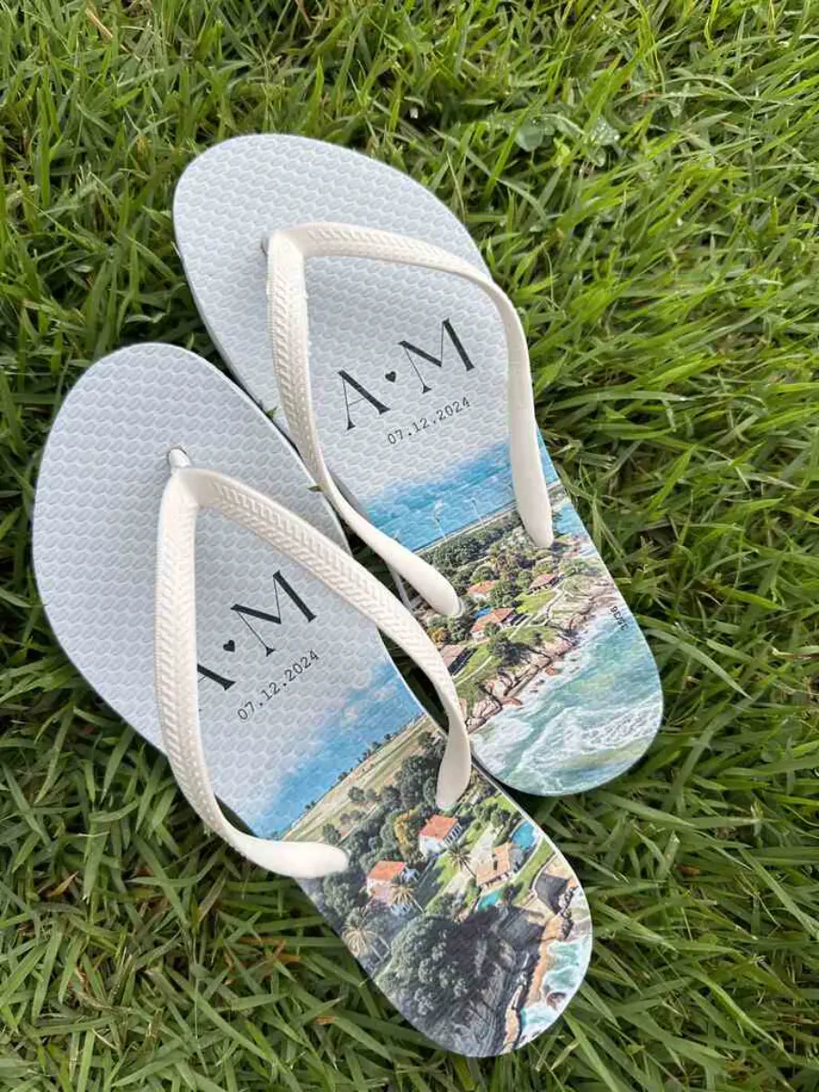 Chinelos personalizados brancos com estampa de paisagem litorânea e iniciais A e M com data do casamento.