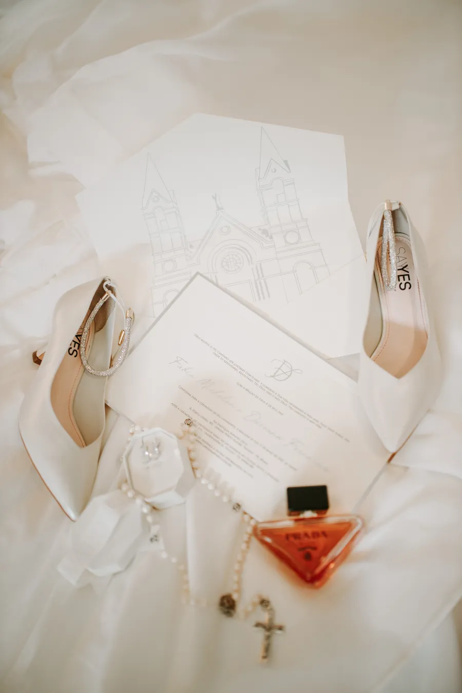 convite de casamento ao lado de sapato de noiva e perfume
