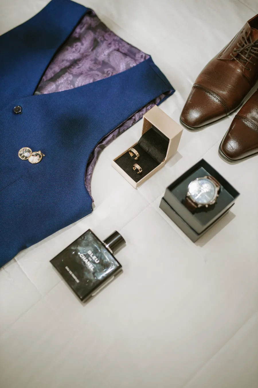colete do noivo ao lado de sapato perfume e relogio