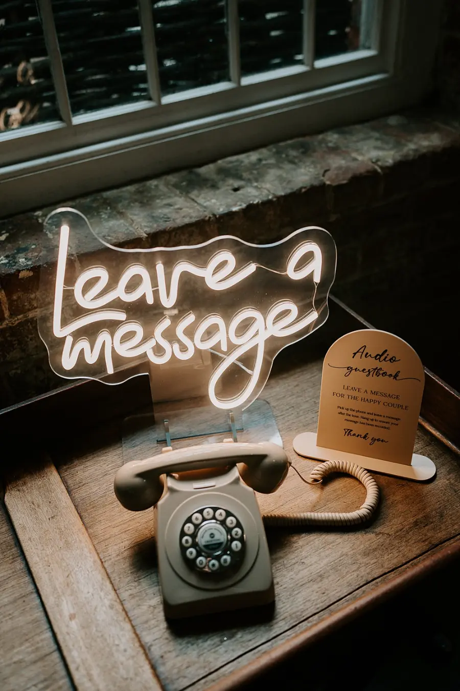 Telefone retrô com um letreiro de néon escrito “Leave a message”.
