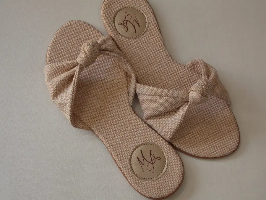 Rasteirinhas personalizadas em tecido bege com nó e iniciais MA no solado.