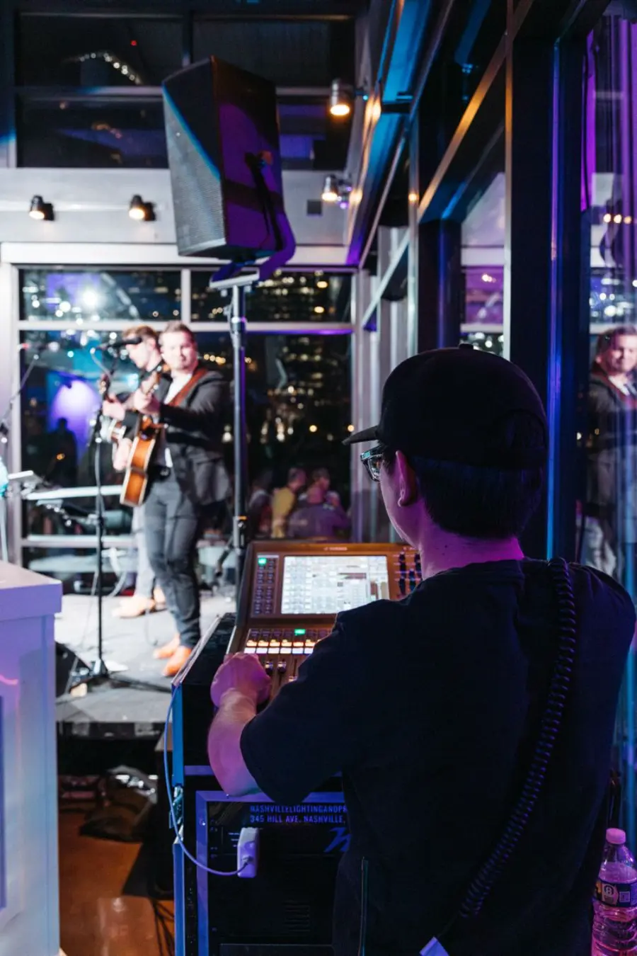 T&eacute;cnico de som controlando mesa digital enquanto banda se apresenta no casamento em sal&atilde;o fechado