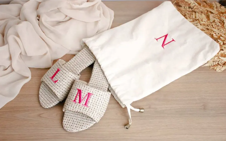 Rasteirinhas personalizadas em palha com iniciais L e M bordadas em rosa, acompanhadas de saquinho de tecido.