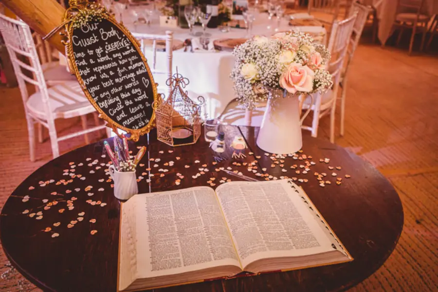 Mesa de recepção com Bíblia aberta para assinaturas, flores e decoração em casamento.