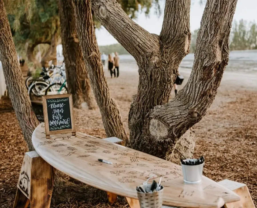 Prancha de surfe de madeira usada como guestbook em casamento de praia com mensagens assinadas pelos convidados.