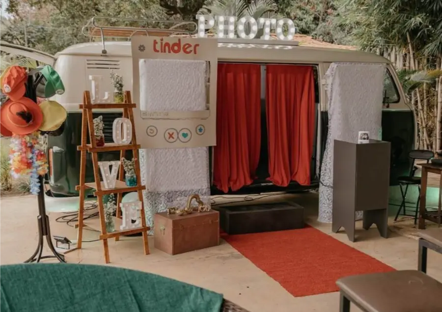 Kombi de fotos para casamento decorada com cortinas vermelhas e adereços temáticos, criando um espaço divertido para os convidados.
