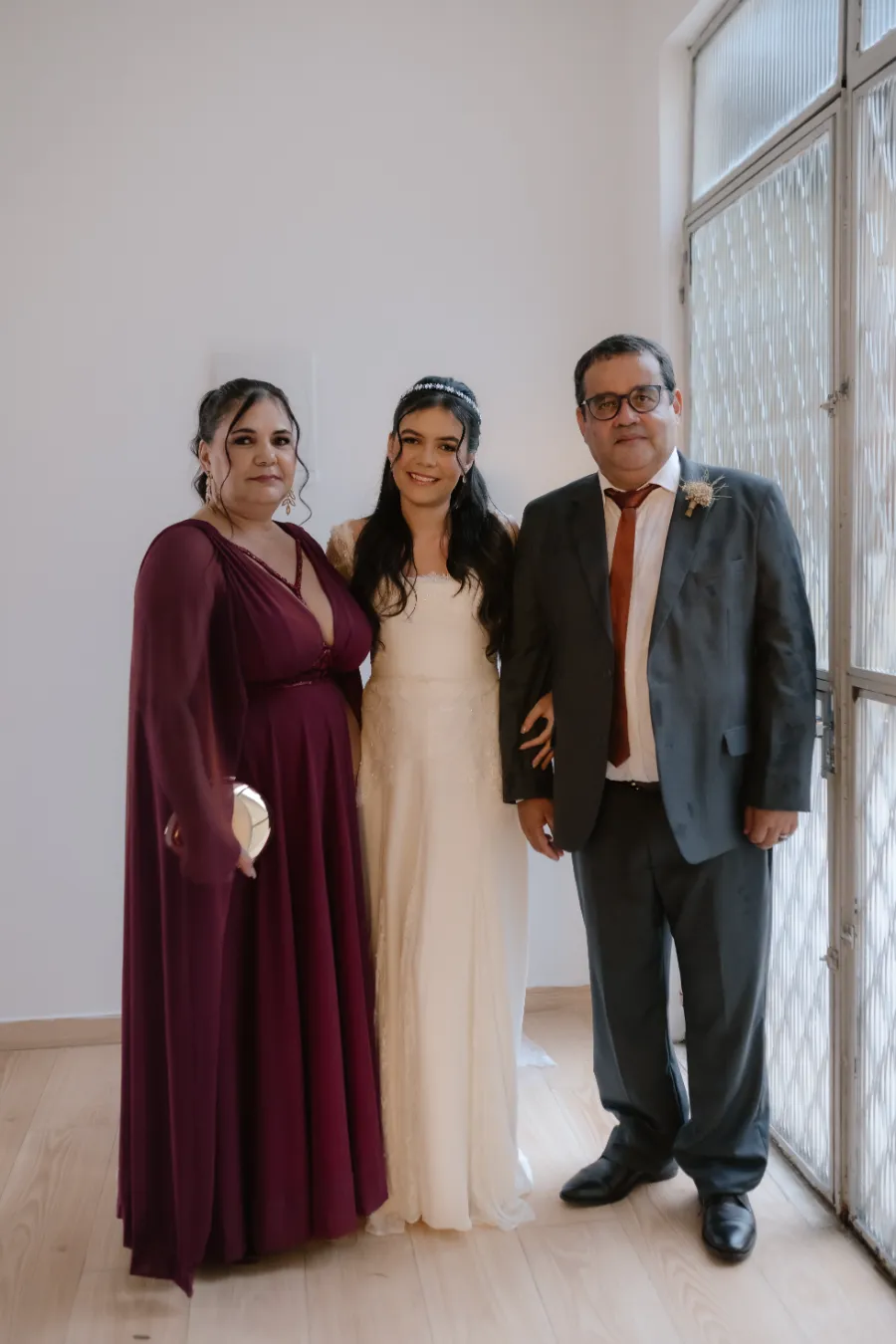 noiva ao lado de mãe com vestido roxo e pai com terno azul