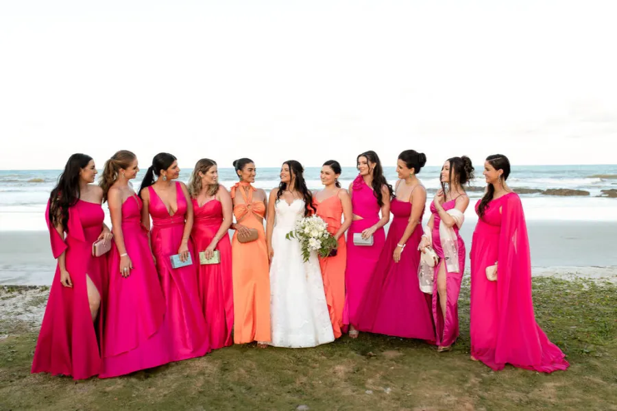 noiva na praia com madrinhas de rosa e laranja em casamento rosa