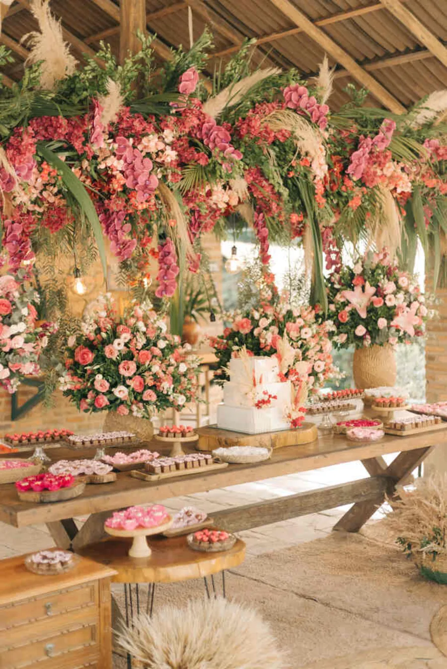 mesa do bolo com flores rosas e capim dos pampas em casamento rosa