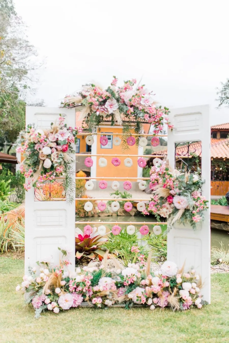 estante edcorada com flores rosas e donuts em casamento rosa