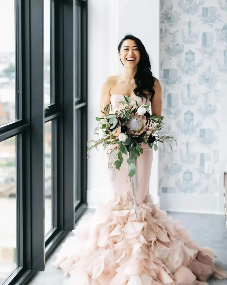 mulher com vestido de noiva rosa sereia e buque