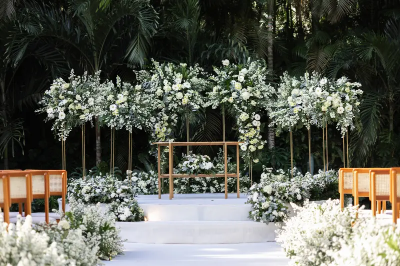 cerimônia ao ar livre com arranjos de flores brancas no pergolado e caminho