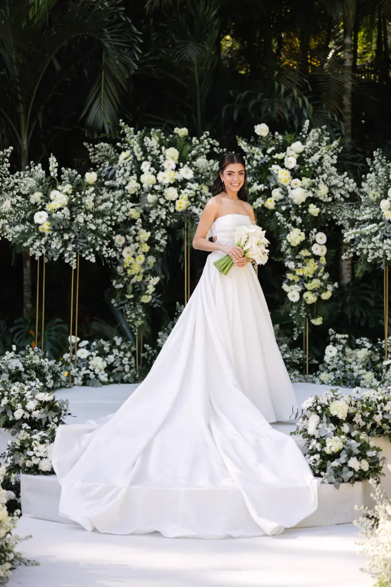 noiva posando em altar com decoração com arranjos de flores brancas